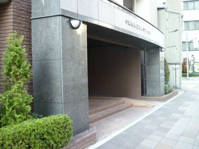 中銀東京日本橋マンシオン エントランス｜エントランスには石調の柱と緩やかなスロープがあり、車椅子やベビーカーの出入りにも配慮された設計。静かな歩道沿いに位置し、落ち着いた印象を与えます。