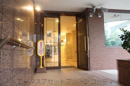シャトー赤坂台エントランス2｜シャトー赤坂台のエントランスはガラス張りの扉と木調フレームの組み合わせで、来訪者に明るい印象を与えます。