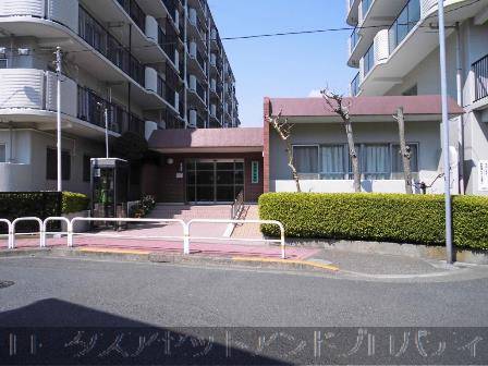 田端スカイハイツエントランス2｜エントランスへは階段を上る形でアプローチで、階段は数段です。ただし階段の段差はそれほど高くなく、タイル張りの床が続いています。エントランスドアはガラス製の大きなドアで開放感があります。