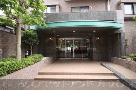 日神パレステージ亀戸第３80112｜エントランスは建物の正面に位置し、数段の階段を上がったところにあります。大きな庇（ひさし）が設けられ、ガラス扉が特徴的です。周囲には緑豊かな植栽が配され、落ち着いた雰囲気を演出しています。