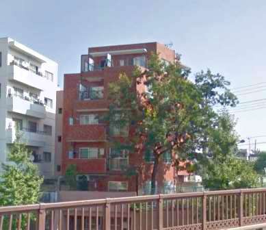 ジェントリー目白の外観。赤茶系タイル張りのファサードが落ち着いた街並みに調和。植栽とセットバック構造により、静かな住環境を演出している。