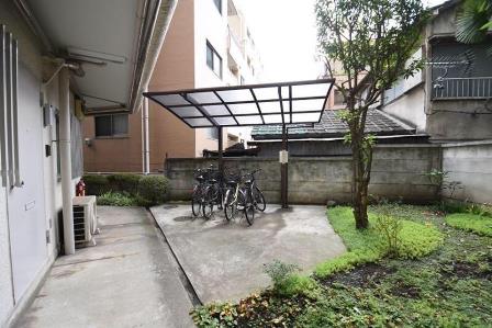 代々木グリーンハイム共用部｜代々木グリーンハイムの駐輪場。屋根付きスペースに複数の自転車が整然と並び、柱と囲いによって天候から守られた構造。敷地内にしっかり確保された日常の足回り設備。