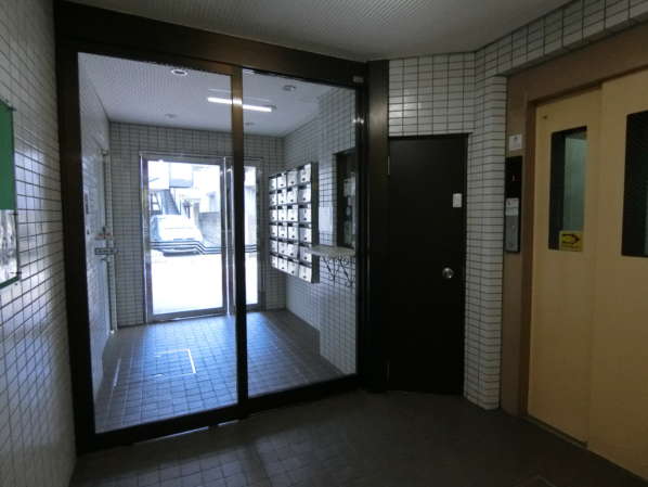 キャッスルマンション千早町外観共用部6｜マンション内部からエントランスを外側に見た画像です。エントランスはこじんまりした様子がわかります。大規模マンションのごとく「だだっ広く」ないので、コンパクトなマンションがお好きな方には向いています。