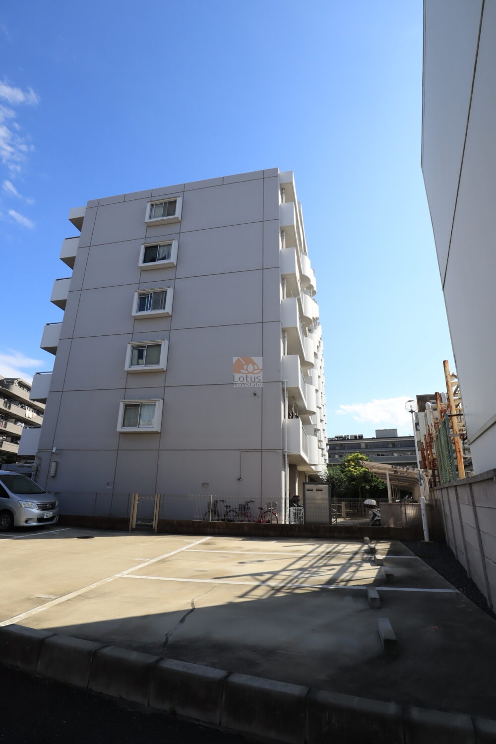 中銀第２城北パークマンシオンの敷地の奥にひっそりと佇む姿。青空に映える白い外壁が爽やかで、裏手には駐輪場と小さな庭が整えられています。少し奥まった立地ですが、その分静かで落ち着いた空気が流れています。