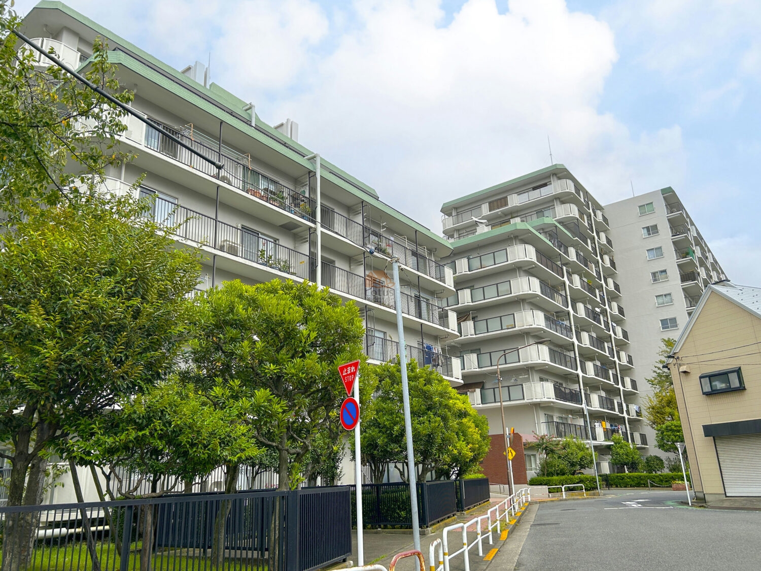 敷地の外周に沿って住棟が連なり、総戸数422戸の規模感が一目で伝わります。白系を基調にした外観と連続するバルコニーが、街路樹の緑とやわらかく馴染む構成です。通りを抜ける風の音が穏やかで、尾久駅徒歩9分という距離感の中でも落ち着いた日常を想像しやすい佇まいといえます。