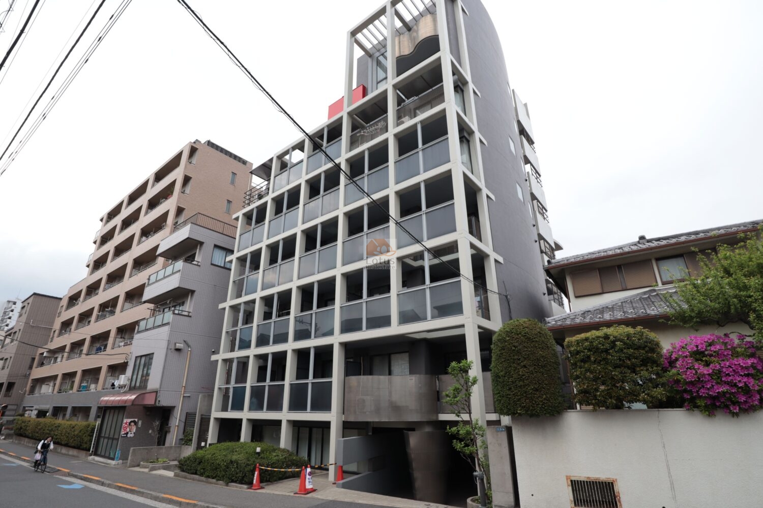 ラミアール門前仲町の外観は、白いフレームとグレー基調の外壁が道路沿いに端正な輪郭を描いています。縦方向のラインが強調され、前面道路との距離が近いけれど圧迫感は控えめ。下町立地の街並みに対して、静かな存在感を保ちながら日常に溶け込む構えです。