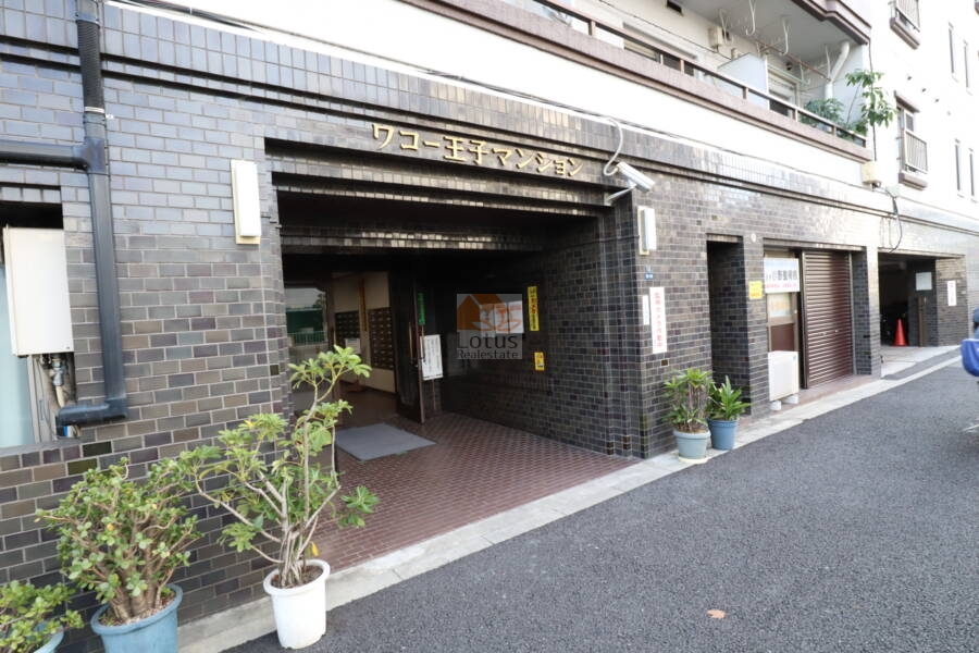 ワコー王子マンションエントランス2｜感じの館名表示は昭和レトロを感じさせるのではないでしょうか。エントランスには防犯カメラが設置されています。