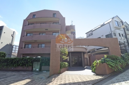 淡いブラウン系タイルを基調にした外観で、緩やかな曲線が印象的です。緑をあしらったアプローチがやわらかい雰囲気をつくり、住宅街の中で落ち着いた存在感を放っています。