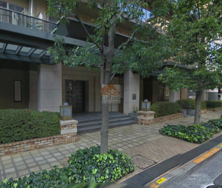西新宿パークサイドタワーエントランス2｜西新宿パークサイドタワーのエントランス周辺です。歩道と敷地の境界は植栽とレンガで整備されており、歩行者にも優しい環境が整っています。エントランス両側の照明や庇が、夜間の安全性も高めています。