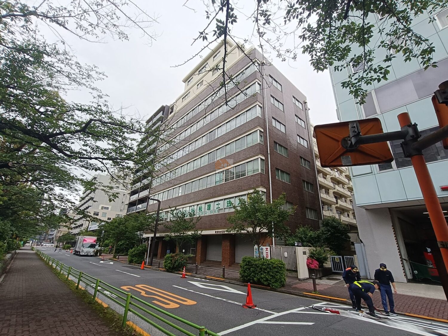 ファミール築地の外観です。明石町の桜並木沿いに建ち、落ち着いたブラウンタイルの外壁が重厚な趣を漂わせています。築地川公園の緑と調和し、年月を経ても整然とした印象を保っています。