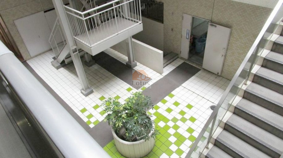 朝日動坂マンション共用部5｜朝日動坂マンションの共用中庭は、白と緑のタイルで視覚的なアクセントを加え、清潔感と遊び心のある空間に仕上がっています。手入れの行き届いた印象です。