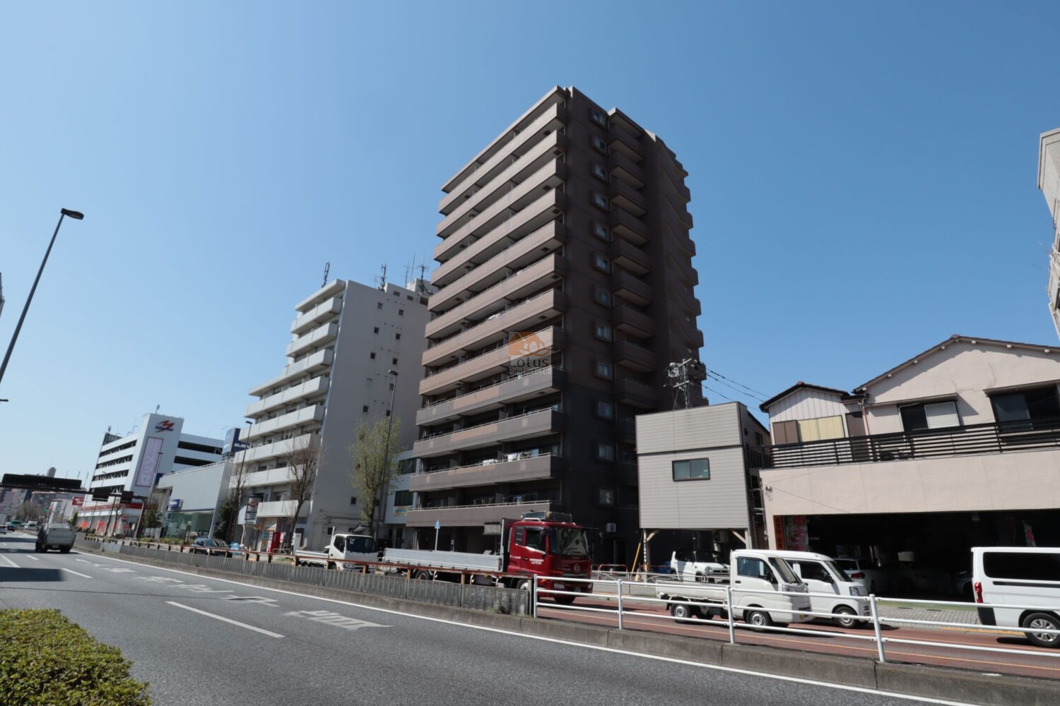 日神パレステージ竹ノ塚第2の外観。国道4号沿いに面し、縦に伸びた形状が道路側から見通しやすい配置です。道路の車線が多いため交通量が安定しており、移動手段を車中心に考える人には便利に感じられます。バルコニーが規則的に並び、住戸ごとの採光方向がそろっている構造とわかります。