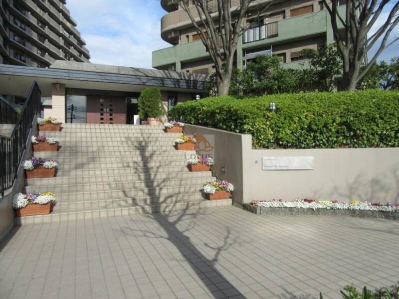 コスモ王子ガーデンズ　グランプラザ外観３｜整備された広場とレンガ調のアプローチがあり、住まいとしての風格とゆとりを演出しています。