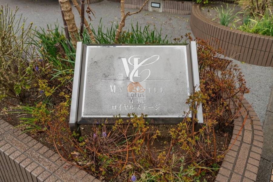マイキャッスル青砥ロイヤルステージ館銘板｜館銘板は、エントランス前に設置されています。英字ロゴと漢字名が刻まれ、物件のブランド性を示しています。