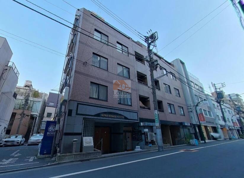 カインドステージ四谷三丁目の外観：レンガ調タイルの外壁と縦に連なるバルコニーが特徴的な中層マンションです。人通りのある通り沿いに建ち、視認性も高い立地です。