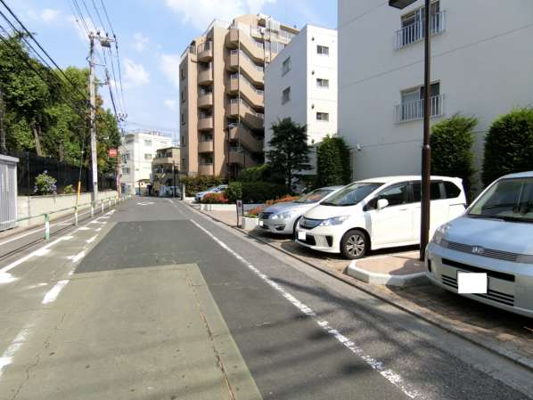 目白ガーデニア外観共用部｜道路を曲がるとすぐマンションの敷地に到達します。写真の左の植栽が高南小学校の敷地です。すなわち学校の目の前にマンションがあります。