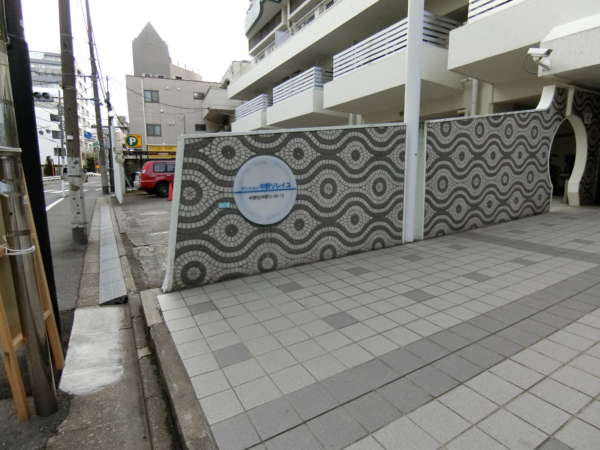 マンション中野ソレイユ外観共用部3｜タイル張りに丸い館銘板が少しかわいらしい感じでした。