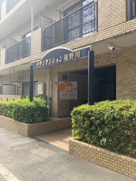 チサンマンション滝野川エントランス１｜エントランスには「サンマンション滝野川」と書かれたサインがあり、植栽に囲まれ、清潔感もあります。