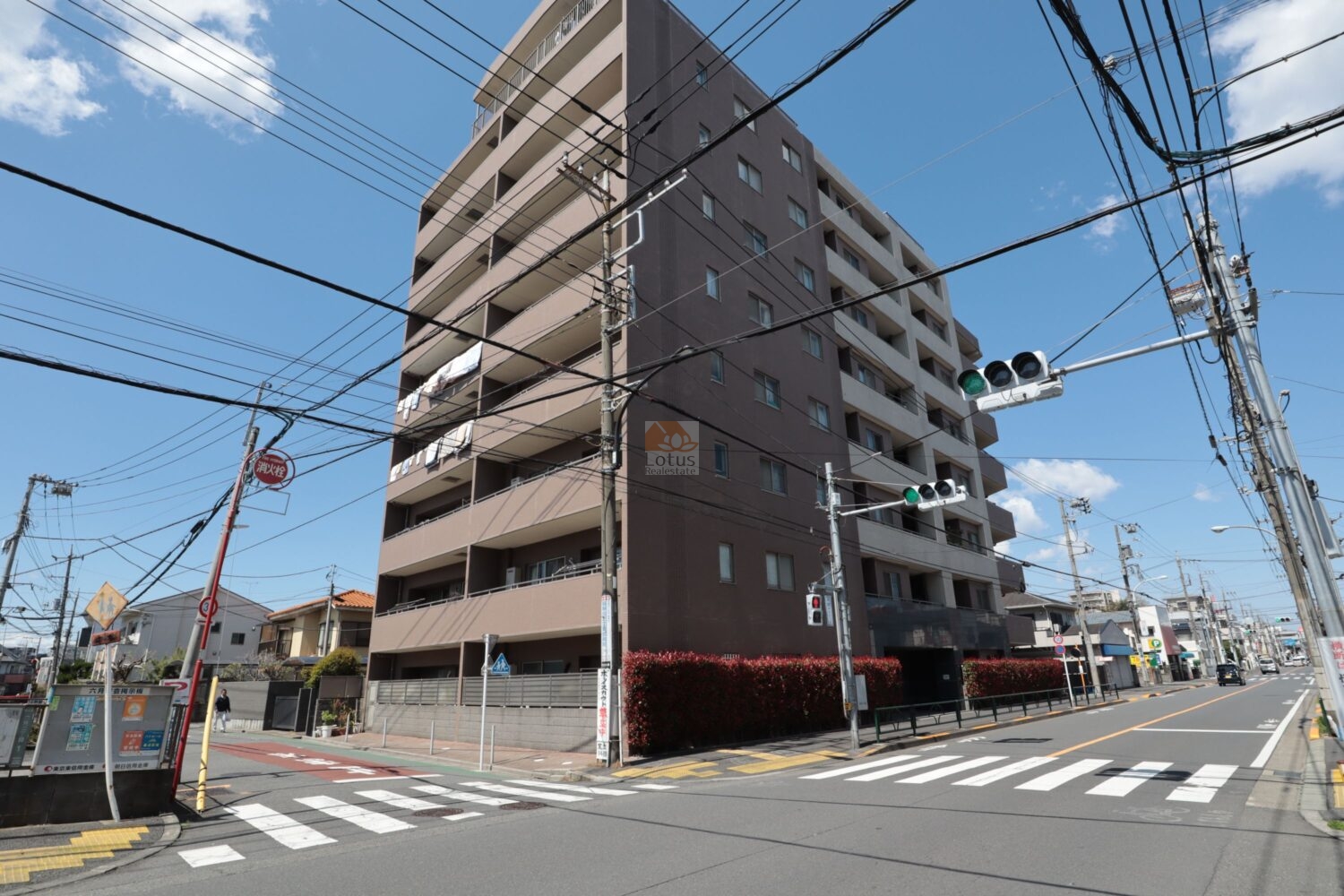 レーベンハイム竹ノ塚ヴィナロスの外観。前面道路は片側一車線で、歩道と自転車の動線が縦方向に伸びています。バルコニーはフラットな手すりで揃えられ、住戸ごとの奥行きが比較的均一に見える配置です。レーベンハイム竹ノ塚ヴィナロスは平成16年築、9階建てのマンションです。