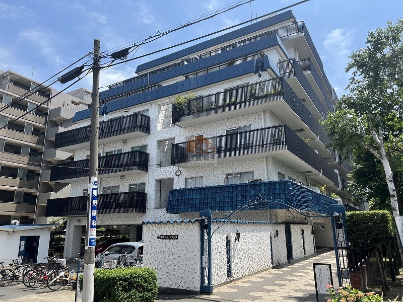 秀和大山レジデンスの外観。グレー系のタイル壁と青い屋根庇、クラシカルな門構えが特徴の7階建てマンション。全戸南向きのバルコニーはブラック手すりで統一され、重厚感と開放感が両立。秀和大山レジデンスは、昭和55年築、7階建てのマンションです。