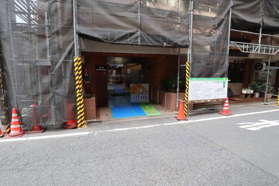新宿パークサイド永谷のエントランス：アプローチにはレンガ調タイルが敷かれ、建物名が刻まれたサインが設置されています。シンプルながらも落ち着いた印象の出入口です。