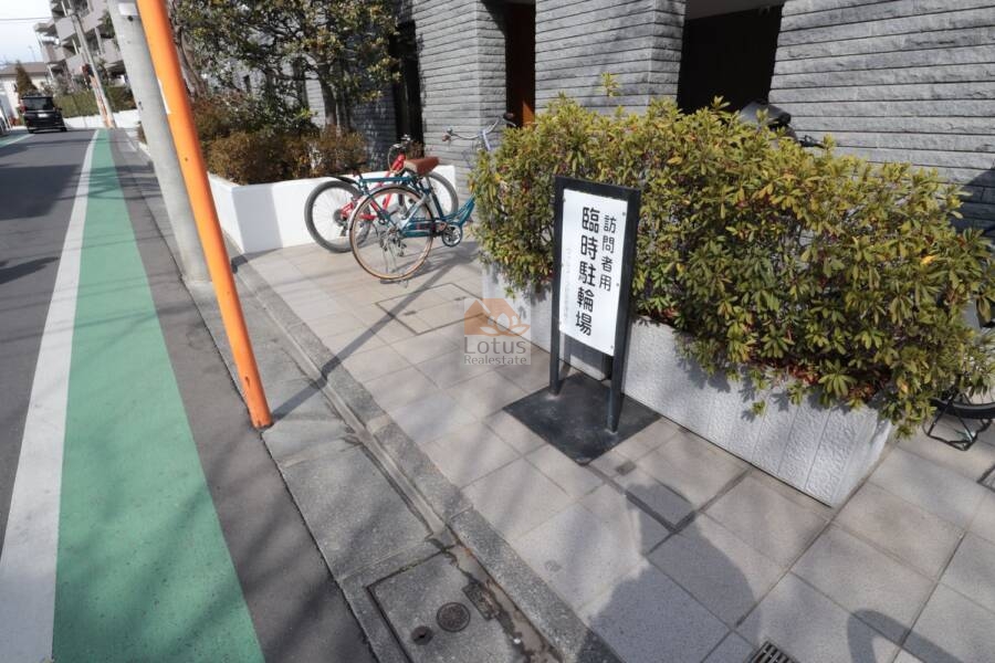 ヴィルヌーブ鷺宮共用部4｜歩道に面して設けられた「訪問者用臨時駐輪場」のサインが、来客への気遣いを表しています。マンション前のスペースを有効に活かした設計です。