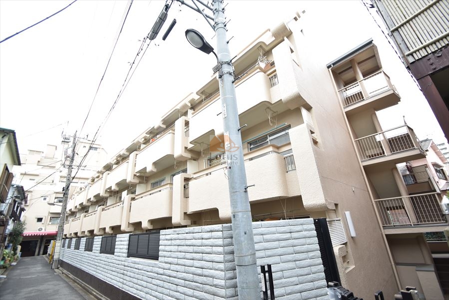 池袋東方マンションは昭和51年築、路地に面した低層5階建の建物は、ベージュ系の吹付外壁と横目地の塀が連続し、都市の雑踏のなかに一定の静けさを保っています。電柱や配線が視界を分断しつつも、奥行きある敷地構成が印象に残ります。