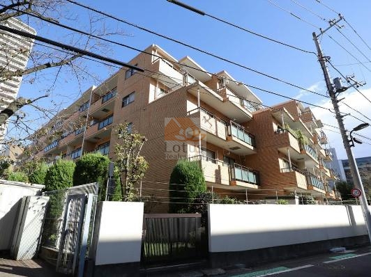 ライオンズマンション新宿原町の外観。煉瓦調の外壁が整然と並び、低層ながらも落ち着いた存在感を放っています。道路沿いには植栽が整えられ、建物と街並みに自然な調和を生み出しています。ライオンズマンション新宿原町は、1983年（昭和58年）11月に建てられた5階建てのマンションです。