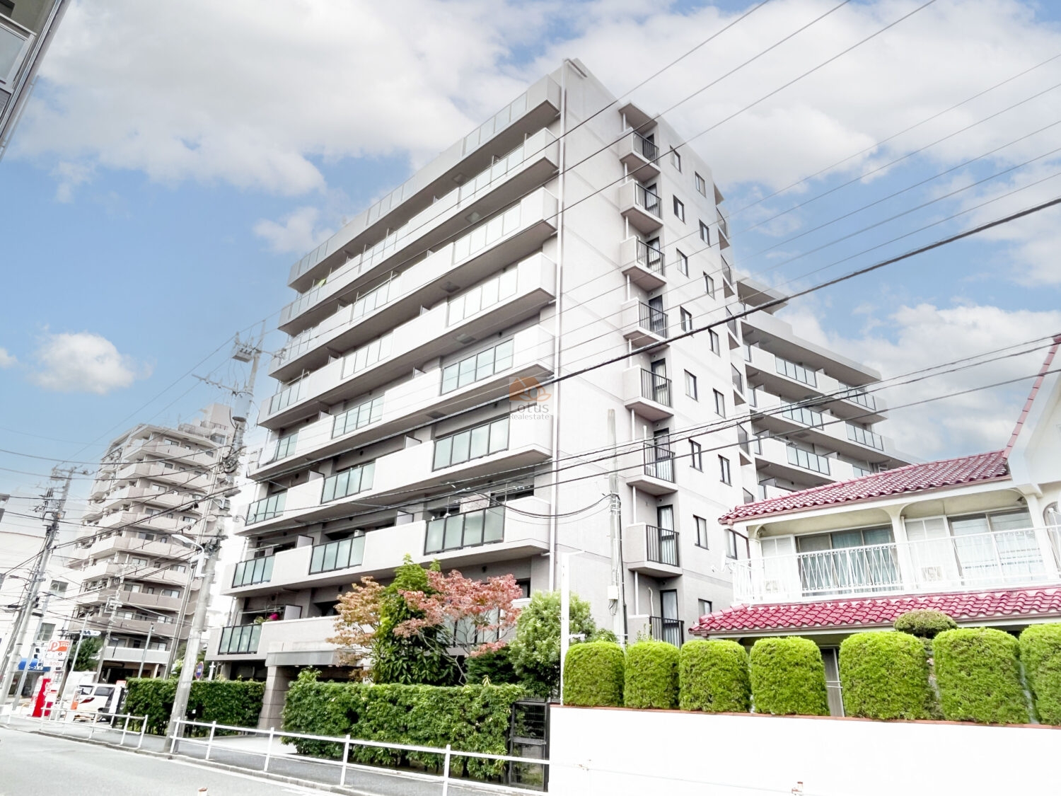 新小岩駅徒歩8分の距離にありながら、通り沿いにゆとりを残した配置が印象に残ります。建物全体は中層9階建で、バルコニーのラインが揃い、空を広く切り取るような見え方です。周囲に低層住宅も混ざるエリアだけに、圧迫感よりも開放感が先に立ち、日中は自然光が外観全体をやわらかく包む住まいです。