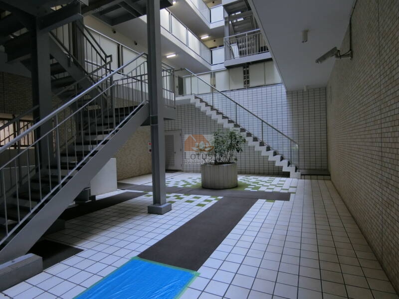朝日動坂マンション共用部4｜朝日動坂マンションの中庭にはアトリウム状の吹き抜けと緑化されたプランターが配置され、共用空間にゆとりと癒しを感じさせます。日常の通行も快適です。
