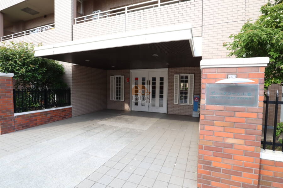 デュークコート小岩エントランス1｜デュークコート小岩マンションのエントランス1：エントランス扉とアプローチが写され、ガラス張りの扉と植栽が印象的です。開放感のある入り口で来訪者を迎えます。