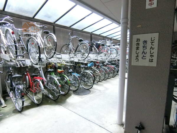 イーストヒル町屋外観共用部4｜駐車場の奥に居住者用の駐輪場があります。