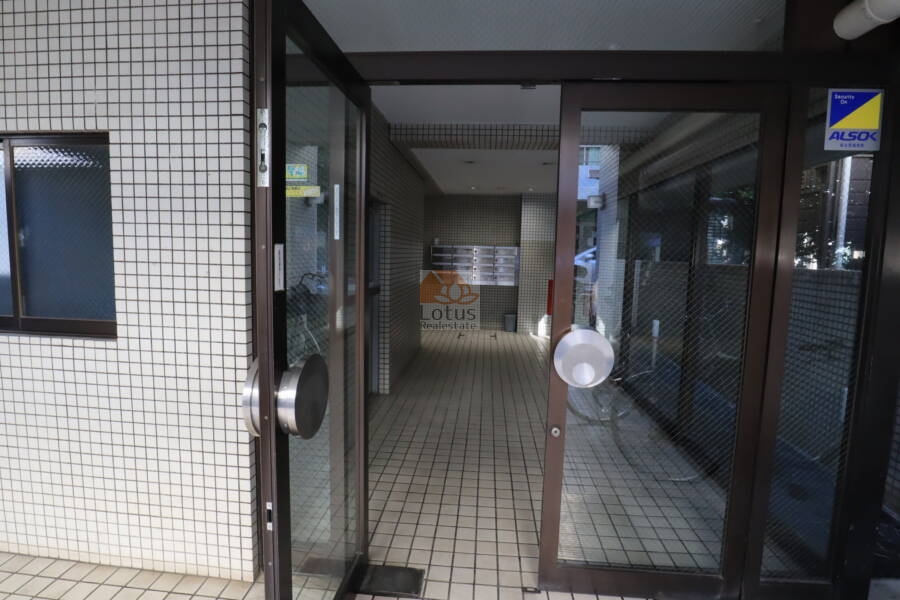 朝日小日向マンションエントランス2｜ガラス扉の奥に集合ポストが整然と並び、安心のALSOKステッカーも確認できます。防犯意識の高さがうかがえる造りです。
