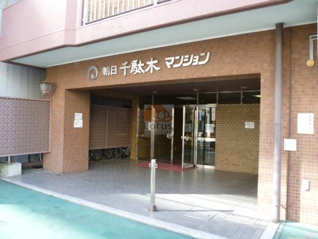 朝日千駄木マンションエントランス (2)｜エントランスは、ガラス張りで外の光をたっぷり取り込み、明るく開かれた印象をつくり出しています。段差の少ないアプローチと広い前面スペースが、日々の出入りにゆとりをもたらしています。
