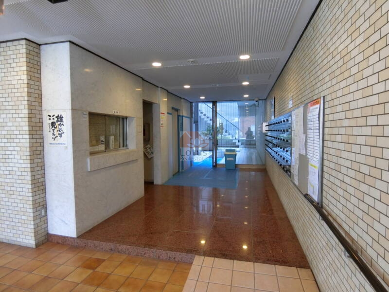 朝日動坂マンション共用部2｜朝日動坂マンションの共用部は管理人窓口付きで、日常の管理体制の良さが伺えます。広めのロビーは採光も確保され、エントランスからの動線が快適に整備されています。