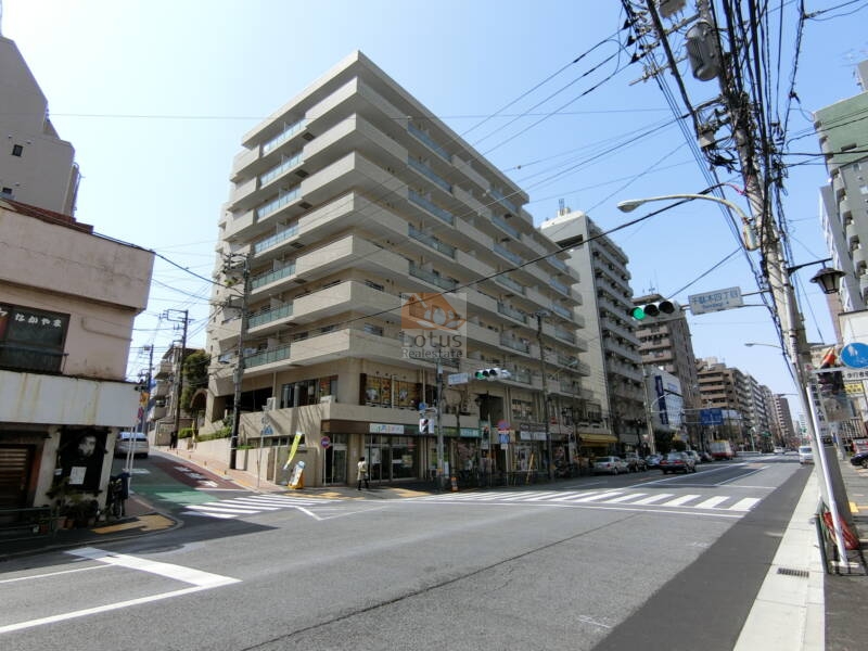 朝日動坂マンション外観2｜朝日動坂マンションの外観2は、千駄木方面からの交差点に面した角地に立地しており、下階にはテナントが並び利便性も兼ね備えています。