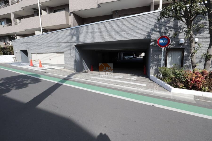 ヴィルヌーブ鷺宮共用部2｜車寄せにもなる屋根付きの駐車場入口は、雨天でも乗り降りしやすい動線を確保。ファサードと調和した石調の壁面が、景観の統一感を演出しています。
