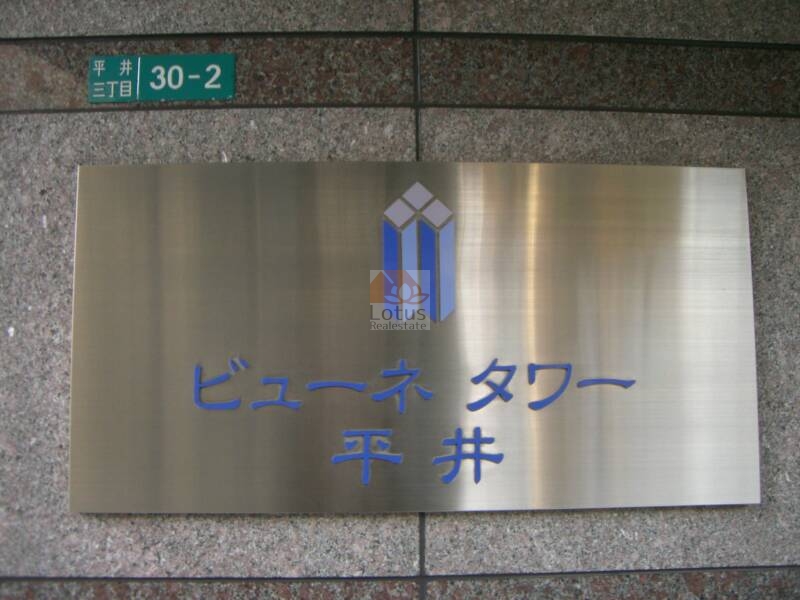 ビューネタワー平井エントランス舘銘板｜館銘板は、御影石調の壁面に、金属プレートで建物名が刻まれています。「平井三丁目30-2」の住所表記も明示され、駅前立地であることが一目でわかるサイン構成です。