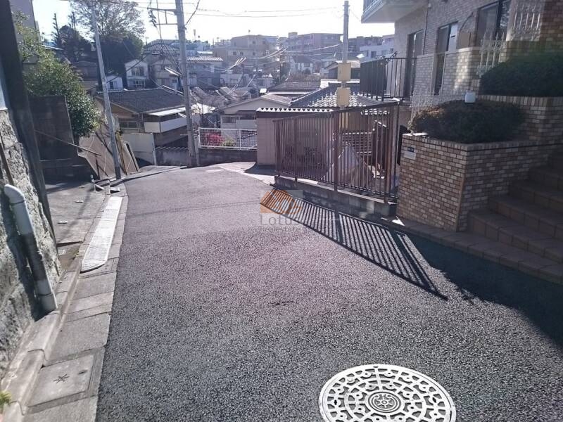 朝日フィオーレ上板橋エントランス前道路｜エントランス前の道路は坂道になっており、通行量は少なく静かな雰囲気です。高低差のある立地が、住戸にゆとりと視界の広がりをもたらしています。