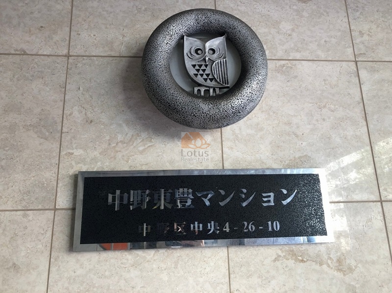 中野東豊マンション外観４｜エントランス壁面に「中野東豊マンション」の館銘板が設置されており、上部にはフクロウの立体装飾が添えられています。視認性が高く、訪問者にも分かりやすい構えです。