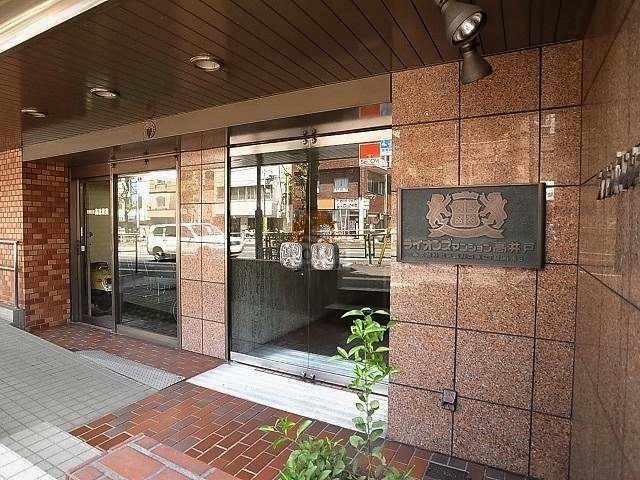 ライオンズマンション高井戸11｜御影石調の壁面とガラス扉が設けられた正面入り口には、建物名を記した重厚な銘板が取り付けられています。