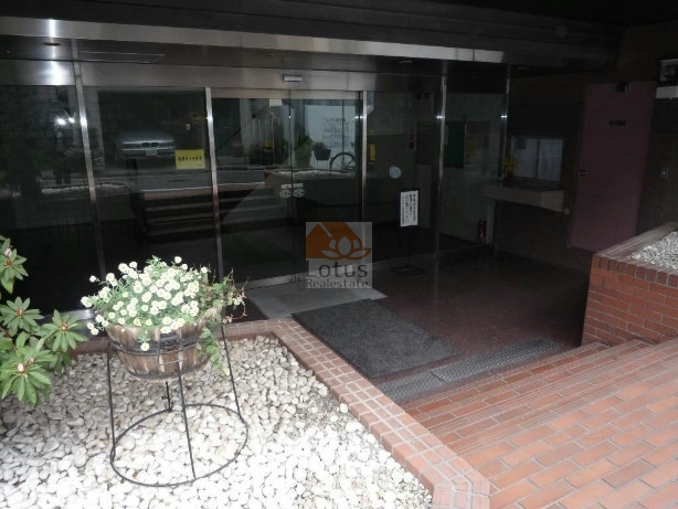 ＧＳハイム小石川エントランス (2)｜エントランスの床タイルが明るさを演出し、建物の重厚な外観とのバランスが取れています。屋根付きのアプローチが雨の日でも安心感を与えてくれます。