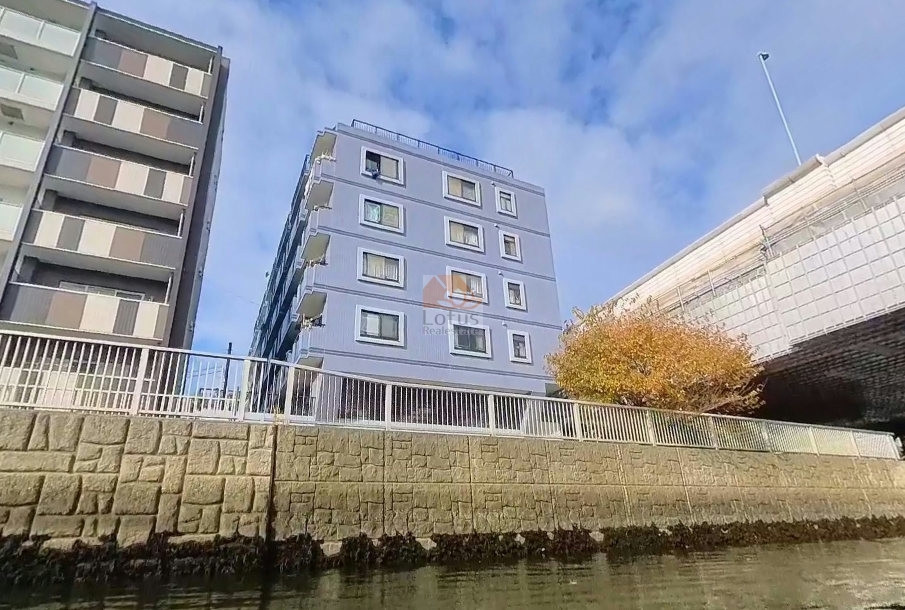 セザール錦糸町を川沿いから見上げた外観で、青系タイル貼りの建物が直線的に並んでいます。右手には首都高速の高架と植栽があり、建物の立地がリバーサイドであることがわかります。セザール錦糸町は、平成７年築、７階建てのマンションです。