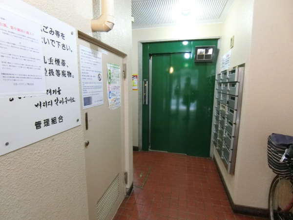 ＧＳハイム新大久保外観共用部6｜奥まったところにエレベータがあります。エレベータ内のカメラがありますので、中の状況もおおむね確認が可能です。外国語の注意書きも見受けられますので、分譲貸しも多いかもしれません。