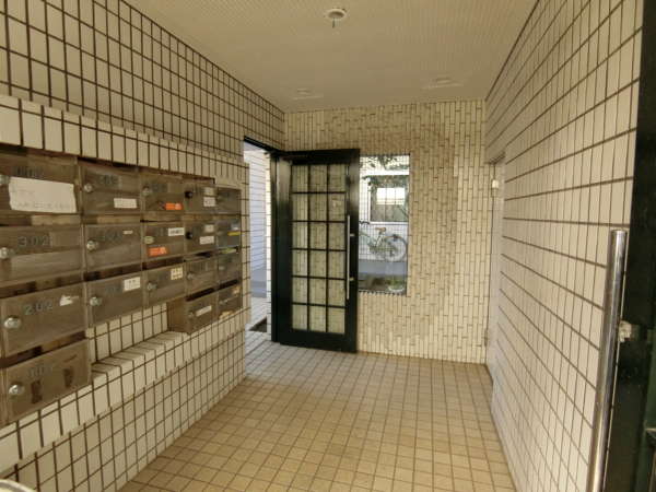 ルミエール東中野外観共用部6｜エントランスの中に入りました。事務所も可のようです。風除室に郵便受けがあり、マンションの規模にしては、すっきりと少し広めに作っています。