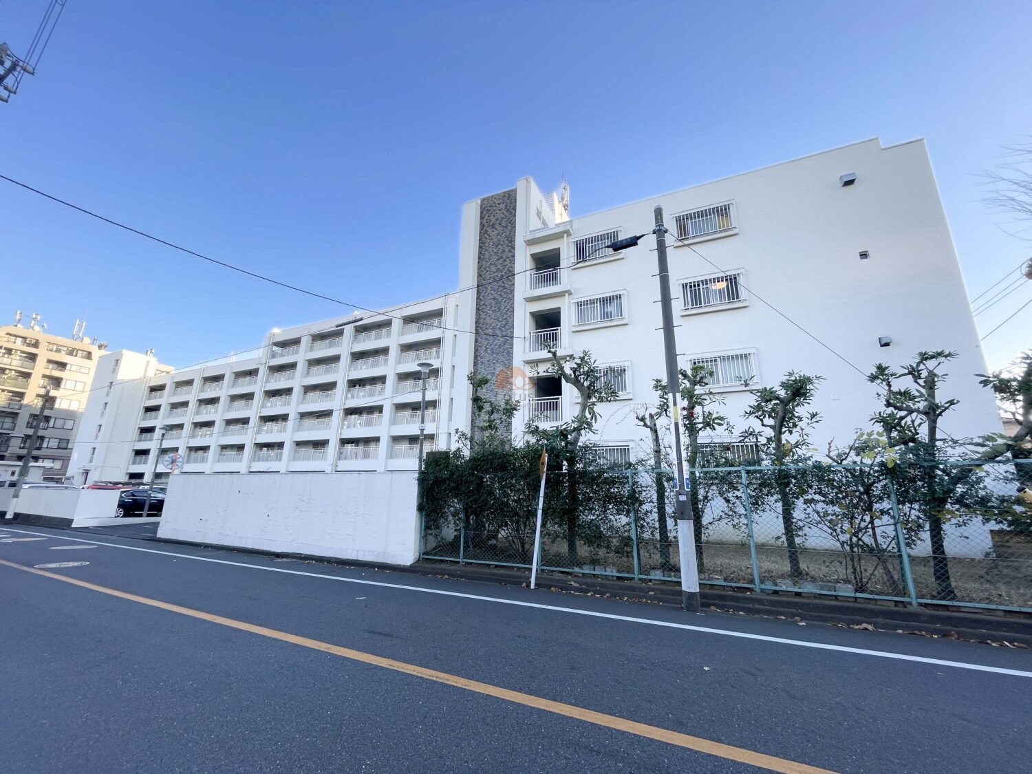 白系外壁の中層住棟が連なる外観です。バス停「南町住宅」徒歩1分の前面道路に沿った配置で、耐震基準適合の団地型構成が確認できます。