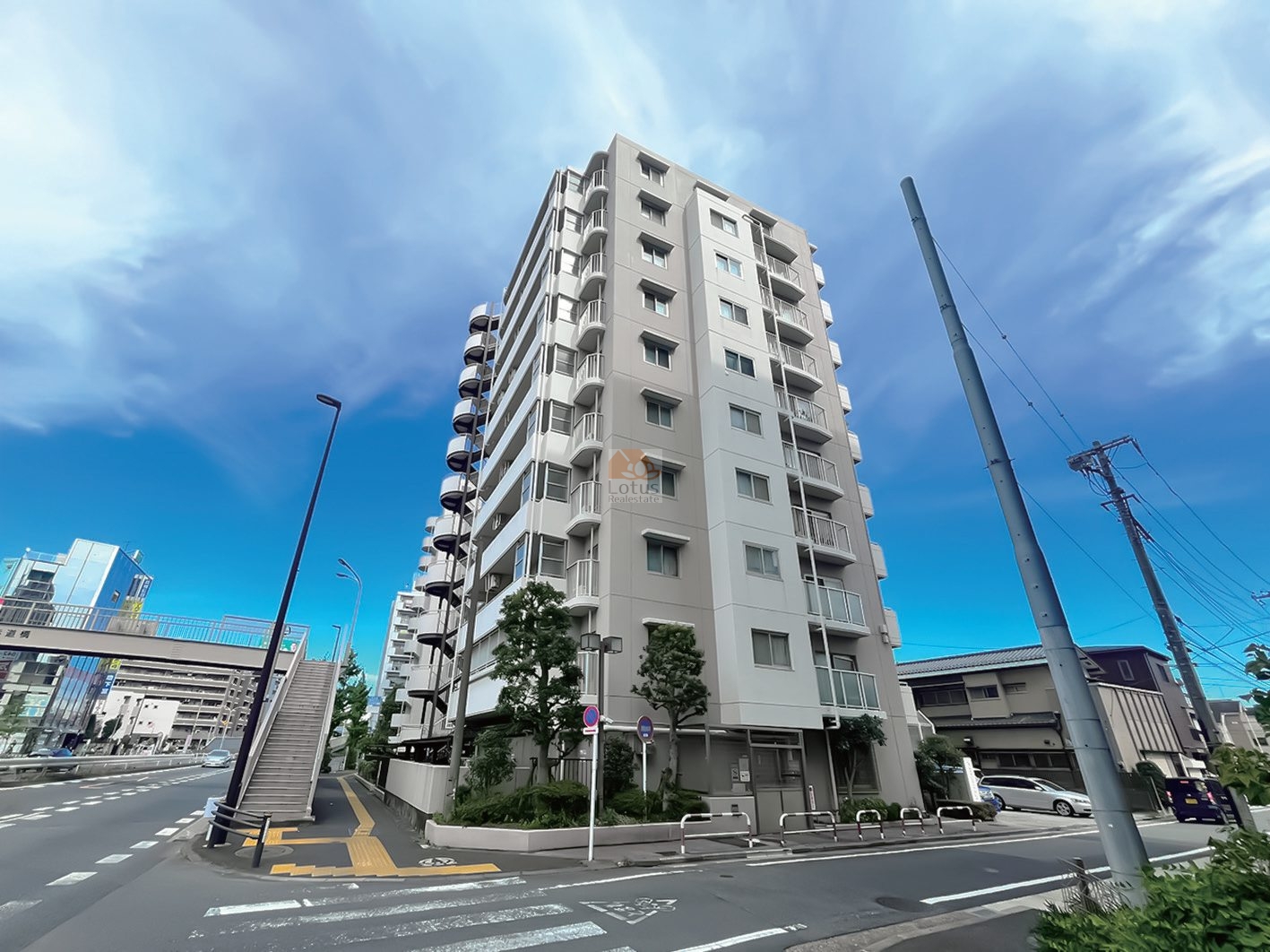 環七通り沿いに立つ中層規模の外観で、角地らしく空が開けた印象です。車通りはありますが、視界が抜けていて距離感は軽やかといえます。