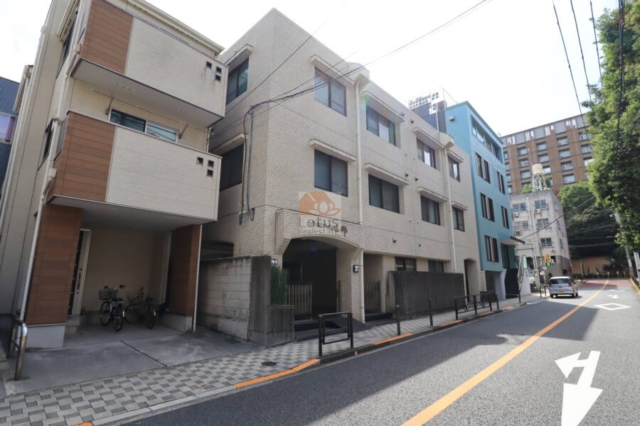 ゾンネンハイム本郷外観2｜周囲に戸建や低層ビルが並ぶ中、ベージュ系タイルとアーチ型のアプローチが印象的な佇まいです。近隣には旧岩﨑庭園や東京大学ある落ち着いた静かな住宅街です。