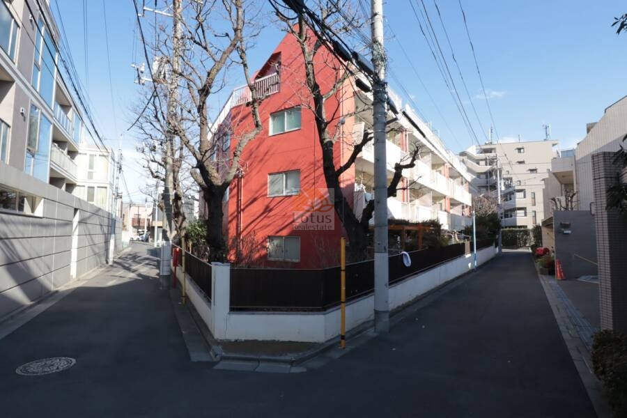 サニーハウスさぎの宮外観2｜角地に立つ赤いファサードが、通りすがりの視線を引き寄せる印象的な外観です。電柱や街路樹との距離感も適度で、閑静な住宅街の中にしっかりと存在感を示しています。