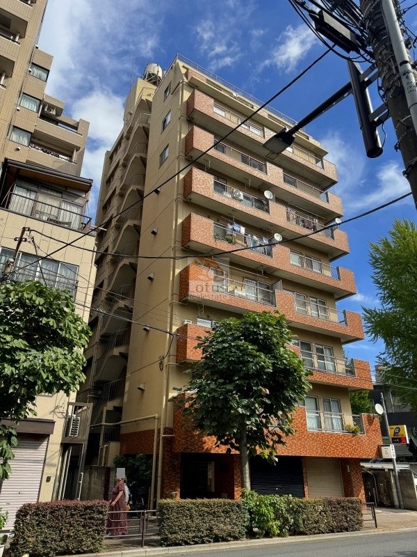 第３鶯谷泰寿院ハイツの外観斜め構図。茶系タイルとベージュの外壁が落ち着いた雰囲気を演出し、通り沿いからも視認性が高い佇まい。駅徒歩２分の立地が伝わる都市型ファサード。第３鶯谷泰寿院ハイツは、昭和54年築、10階建てのマンションです。